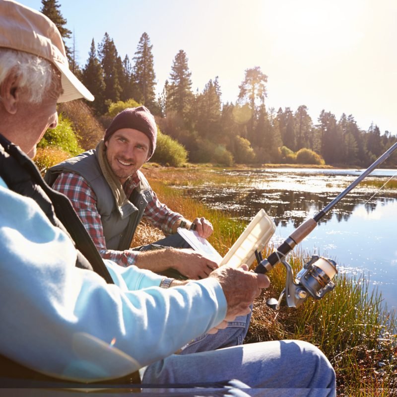 Father and adult son fishing lakeside, close-up